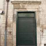 ...e la fondazione muraria che appare in forte contrasto con la moderna saracinesca verde di un negozio con cui convive